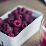glass of juice and a bowl of raspberries fruits