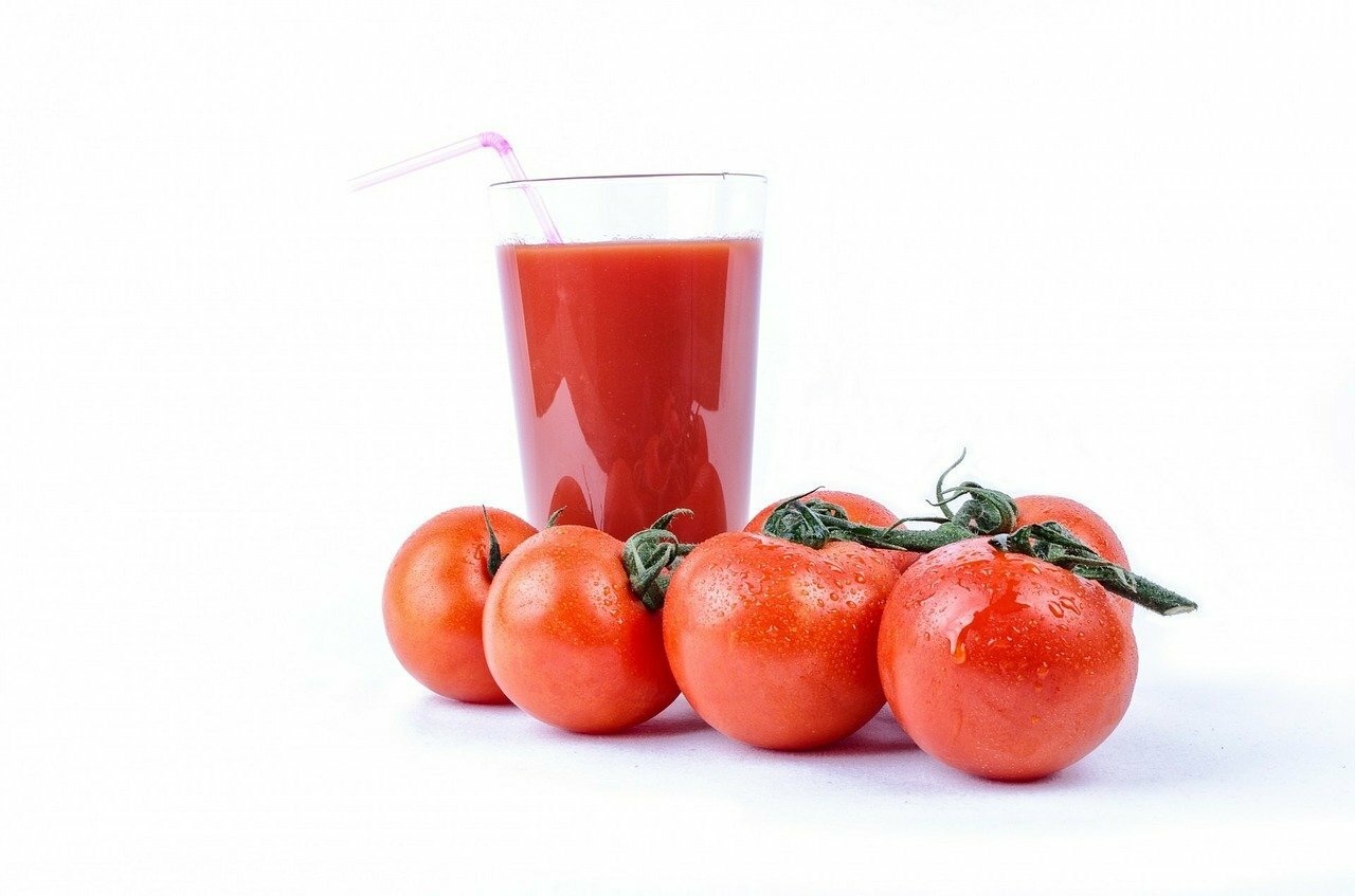 glass tomato juice and tomatoes next to it